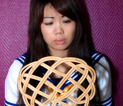 asian schoolgirl holding the carpet beater she\'s about to be spanked with