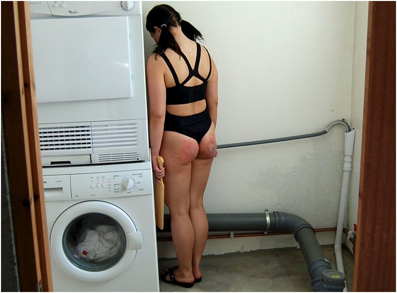 woman with paddled ass holds her nose to the corner in the basement laundry room