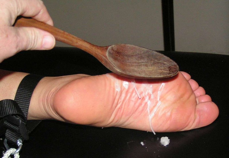 spanking her wax-coated feet with a wooden spoon