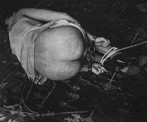 woman lying in bondage after being whipped with a martinet
