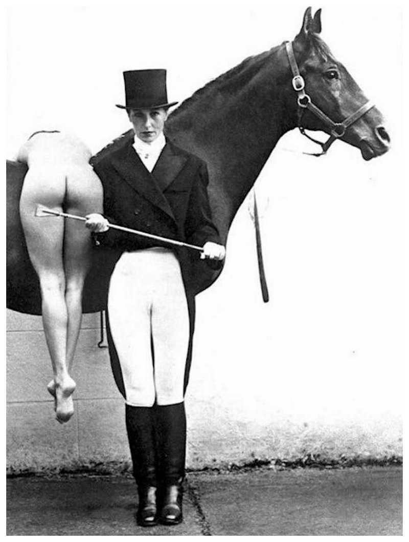 severe horsewoman in dressage outfit stands ready to spank a naked woman over the back of a tall show horse