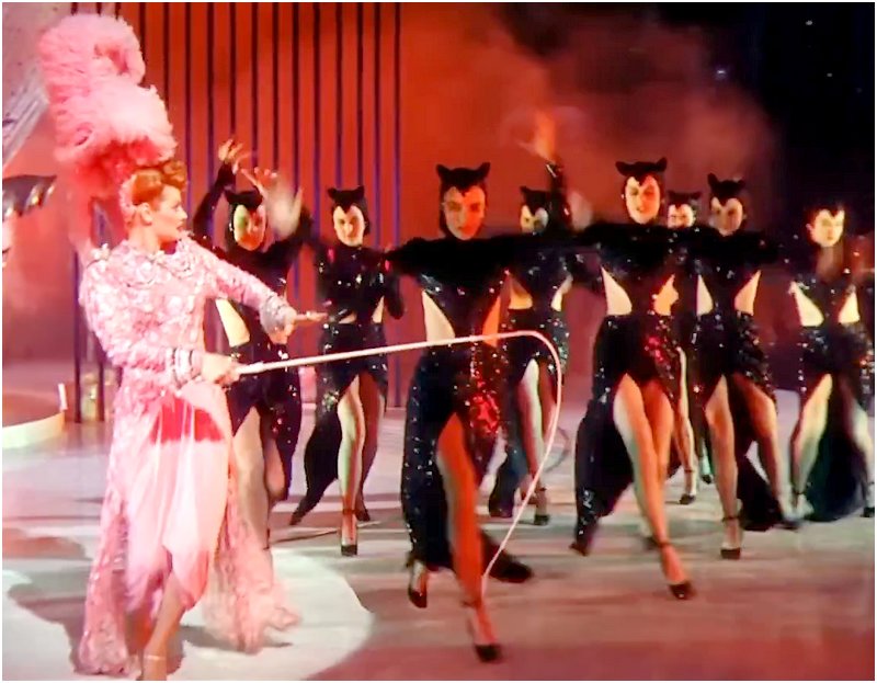 Lucille Ball herding catgirls through a burlesque dance number with a long whip