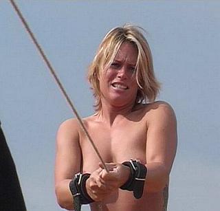 cuffed nude woman on whip-enforced march in the sunshine