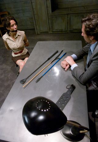 pretty female detainee threatened with spanking and caning in the interrogation room