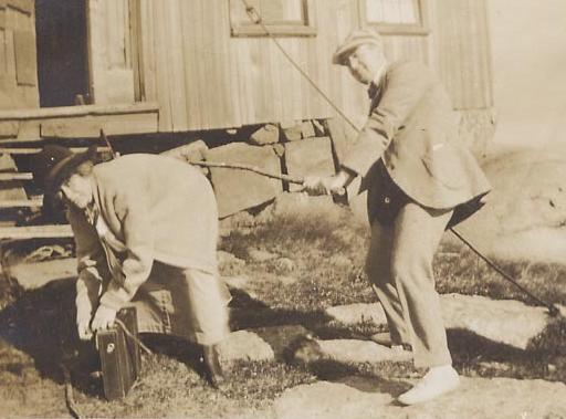 vintage postcard scene of a man spanking a woman with a big stick as she bends over her luggage