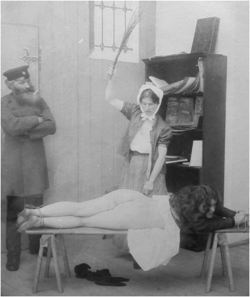 Vintage photograph of a woman tied to a spanking bench while being birched by a servant as a uniformed military officer supervises the punishment