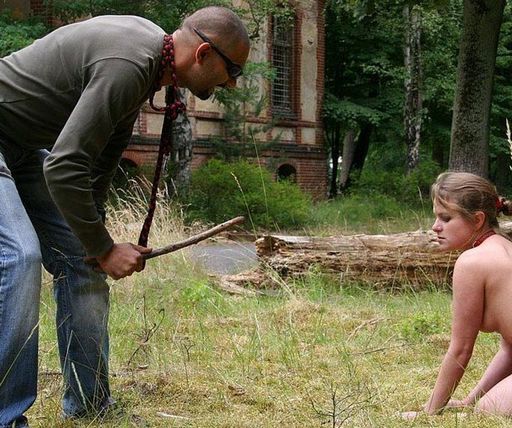 nude kneeling woman being offered a choice: fetch the stick, or be spanked with it?