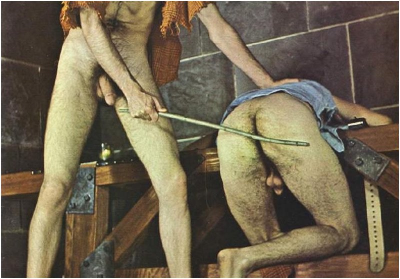 gay man bent over a basement shop workbench for a caning and a leather belt spanking